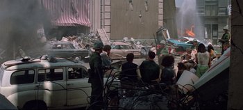 Movie still from “Earthquake” (1974), directed by Mark Robson – A group of people sitting in a parking lot next to a building; Wide shot, High angle