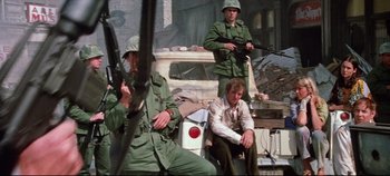 Movie still from “Earthquake” (1974), directed by Mark Robson – A group of men sitting next to each other in front of a car; Wide shot, Low angle