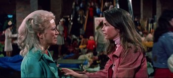 Movie still from “Earthquake” (1974), directed by Mark Robson – Two women talking to each other in front of a group of people; Medium shot, Over the shoulder angle
