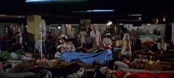 Movie still from “Earthquake” (1974), directed by Mark Robson – A group of people sitting in a room with many bags of luggage; Wide shot, High angle