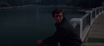 Movie still from “Earthquake” (1974), directed by Mark Robson – A man standing in front of a body of water at night; Medium shot, Over the shoulder angle