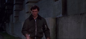 Movie still from “Earthquake” (1974), directed by Mark Robson – A man standing in a dark room holding a cigarette; Medium shot, Low angle