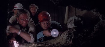 Movie still from “Earthquake” (1974), directed by Mark Robson – A man holding a flashlight in the dark; Medium shot, Low angle