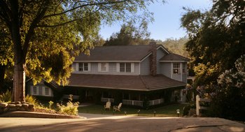 Movie still from “Easy A” (2010), directed by Will Gluck – A large house with a lawn chair in front of it; Extreme Wide shot, High angle