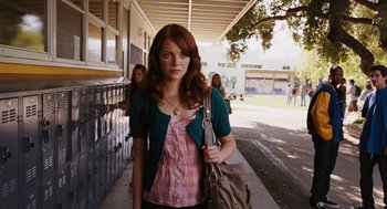 Movie still from “Easy A” (2010), directed by Will Gluck – A woman holding a purse while standing on a sidewalk; Medium shot, Over the shoulder angle
