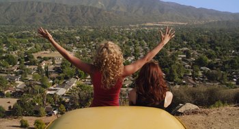 Movie still from “Easy A” (2010), directed by Will Gluck – Two women riding a roller coaster with their hands up; Extreme Wide shot, High angle
