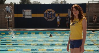 Movie still from “Easy A” (2010), directed by Will Gluck – A woman standing next to a swimming pool; Medium shot, Over the shoulder angle