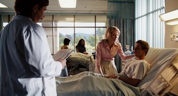 Movie still from “Easy A” (2010), directed by Will Gluck – A man in a hospital bed talking to a woman in front of a doctor; Medium shot, Over the shoulder angle