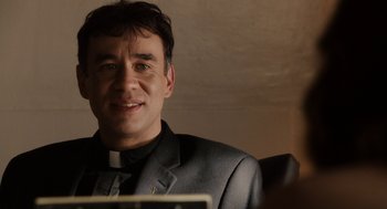 Movie still from “Easy A” (2010), directed by Will Gluck – A man wearing a suit and tie smiling for the camera; Close Up shot, Over the shoulder angle