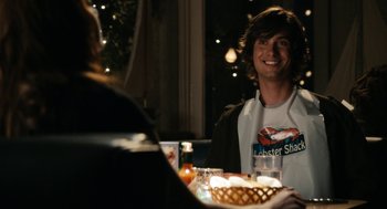 Movie still from “Easy A” (2010), directed by Will Gluck – A man sitting at a dinner table with a lobster shack shirt on; Close Up shot, Over the shoulder angle