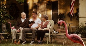 Movie still from “Easy A” (2010), directed by Will Gluck – Three people sitting on a bench in front of a pink flamingo; Wide shot, Over the shoulder angle