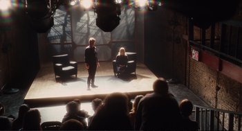 Movie still from “Eat Pray Love” (2010), directed by Ryan Murphy – A couple of people are sitting on a stage; Wide shot, High angle