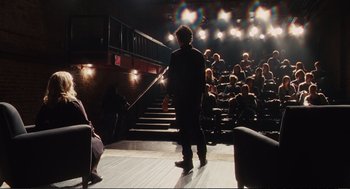 Movie still from “Eat Pray Love” (2010), directed by Ryan Murphy – A man standing in front of an audience on a stage; Wide shot, High angle