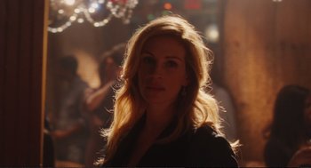 Movie still from “Eat Pray Love” (2010), directed by Ryan Murphy – A woman with long blonde hair standing in front of a crowd; Close Up shot, Over the shoulder angle