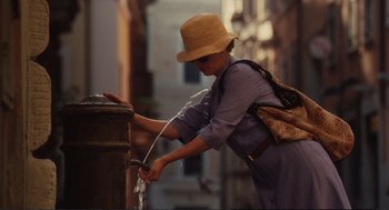 Movie still from “Eat Pray Love” (2010), directed by Ryan Murphy – A woman in a straw hat is filling up a water bottle; Medium shot, Over the shoulder angle