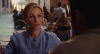 Movie still from “Eat Pray Love” (2010), directed by Ryan Murphy – A woman in a blue shirt sitting in front of a group of people; Close Up shot, Over the shoulder angle