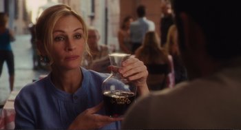 Movie still from “Eat Pray Love” (2010), directed by Ryan Murphy – A woman holding a glass of wine in a restaurant; Close Up shot, Over the shoulder angle