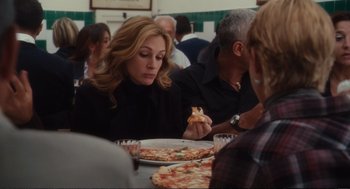 Movie still from “Eat Pray Love” (2010), directed by Ryan Murphy – A group of people sitting around a table eating pizza; Medium shot, Over the shoulder angle
