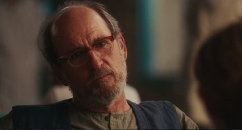 Movie still from “Eat Pray Love” (2010), directed by Ryan Murphy – An older man wearing glasses and a vest; Close Up shot, Over the shoulder angle