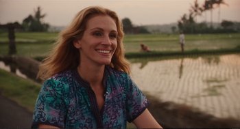 Movie still from “Eat Pray Love” (2010), directed by Ryan Murphy – A woman smiling while standing next to a body of water; Medium shot, Over the shoulder angle