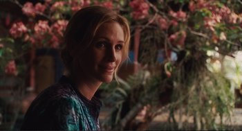Movie still from “Eat Pray Love” (2010), directed by Ryan Murphy – A woman with blonde hair is smiling for the camera; Close Up shot, Over the shoulder angle