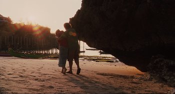 Movie still from “Eat Pray Love” (2010), directed by Ryan Murphy – Two people hugging on the beach near a large rock; Wide shot, Low angle