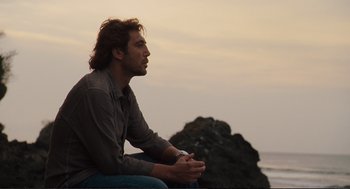 Movie still from “Eat Pray Love” (2010), directed by Ryan Murphy – A man sitting on a rock looking out at the ocean; Medium shot, Low angle