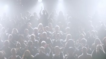 Movie still from “Black Mirror” (2011), created by Charlie Brooker – A large group of people in a dark room; Extreme Wide shot, High angle
