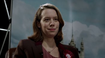 Movie still from “Black Mirror” (2011), created by Charlie Brooker – A person wearing a suit and tie; Close Up shot, Low angle