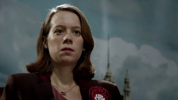 Movie still from “Black Mirror” (2011), created by Charlie Brooker – A woman in a red jacket is looking into the distance; Close Up shot, Low angle