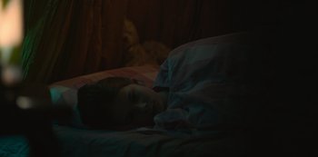 Movie still from “Equinox” (2020), directed by Søren Balle – A girl is sleeping in a bed with a blanket; Close Up shot, High angle
