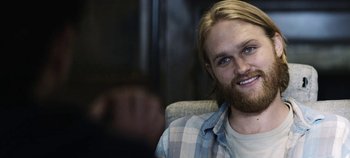 Movie still from “Black Mirror” (2011), created by Charlie Brooker – A person with long hair and a beard; Close Up shot, Over the shoulder angle