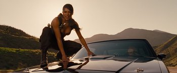 Movie still from “Fast & Furious” (2009), directed by Justin Lin – A woman leaning on the hood of a car; Medium shot, Low angle