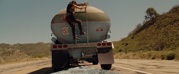 Movie still from “Fast & Furious” (2009), directed by Justin Lin – A person climbing on the back of a tanker truck; Wide shot, Low angle