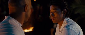 Movie still from “Fast & Furious” (2009), directed by Justin Lin – A man standing next to another man in front of a fire; Close Up shot, Over the shoulder angle