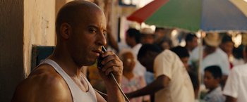 Movie still from “Fast & Furious” (2009), directed by Justin Lin – A man talking on a cell phone while standing next to a crowd of onlookers; Close Up shot, Over the shoulder angle