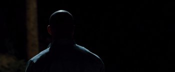 Movie still from “Fast & Furious” (2009), directed by Justin Lin – A man in a black shirt is standing in front of a black background; Close Up shot, Low angle