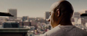 Movie still from “Fast & Furious” (2009), directed by Justin Lin – A bald headed man looking out over a city; Close Up shot, Over the shoulder angle