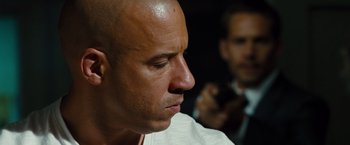 Movie still from “Fast & Furious” (2009), directed by Justin Lin – A bald headed man with his eyes closed looking down; Close Up shot, Over the shoulder angle