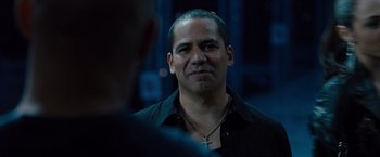 Movie still from “Fast & Furious” (2009), directed by Justin Lin – A person wearing a black shirt and a cross necklace; Close Up shot, Over the shoulder angle