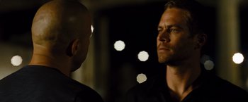 Movie still from “Fast & Furious” (2009), directed by Justin Lin – A man looking at another man in a dark room; Close Up shot, Over the shoulder angle
