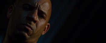 Movie still from “Fast & Furious” (2009), directed by Justin Lin – A bald man's face with a dark background; Close Up shot, Low angle