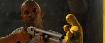 Movie still from “Fast & Furious” (2009), directed by Justin Lin – A man holding a gun in front of a statue; Close Up shot, Over the shoulder angle