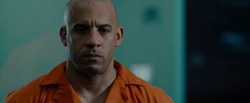 Movie still from “Fast & Furious” (2009), directed by Justin Lin – A man in an orange shirt is looking at the camera; Close Up shot, Over the shoulder angle