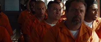 Movie still from “Fast & Furious” (2009), directed by Justin Lin – A group of men in orange shirts are lined up in a row; Medium shot, Over the shoulder angle