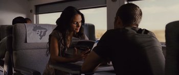 Movie still from “Fast Five” (2011), directed by Justin Lin – A woman sitting at a table reading a magazine; Medium shot, Over the shoulder angle
