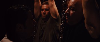 Movie still from “Fast Five” (2011), directed by Justin Lin – A man standing next to another man in chains; Medium shot, Over the shoulder angle