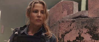 Movie still from “Fast Five” (2011), directed by Justin Lin – A woman in a black shirt is standing in front of a stone wall; Close Up shot, Over the shoulder angle