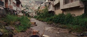 Movie still from “Fast Five” (2011), directed by Justin Lin – A man standing on the side of a river near houses; Wide shot, High angle