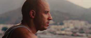 Movie still from “Fast Five” (2011), directed by Justin Lin – A bald man looking out of a window at a city; Close Up shot, Over the shoulder angle
